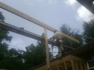 Carpenter setting a ridge beam over a new addition frame — Ice Dam Removal by Roofing Brothers in Pine Meadow