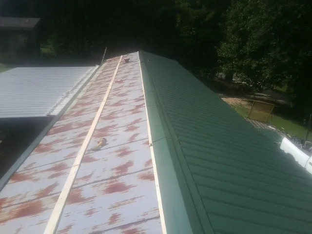 Old rusted panels beside newly installed green metal roofing — Wind Damage Roof Repair by Roofing Brothers in Pine Meadow