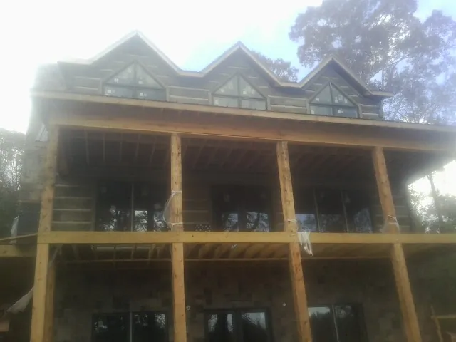 Dormers and porch framing on a large log home under construction — Roof Coating work by our crew in Pine Meadow