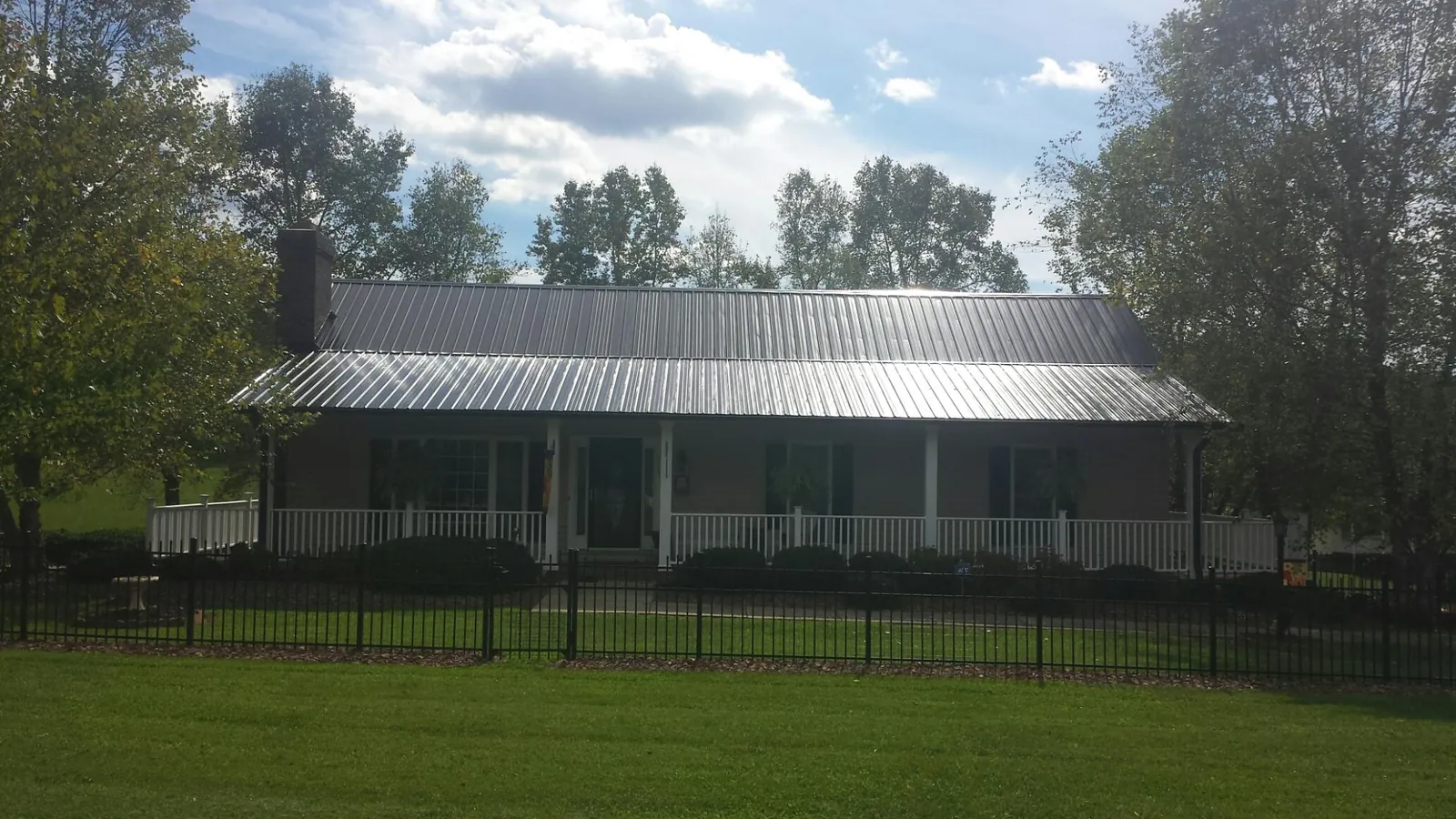 Gray metal roof on a brick ranch with a full width front porch — Gutter Guard Installation work by our crew in Pine Meadow
