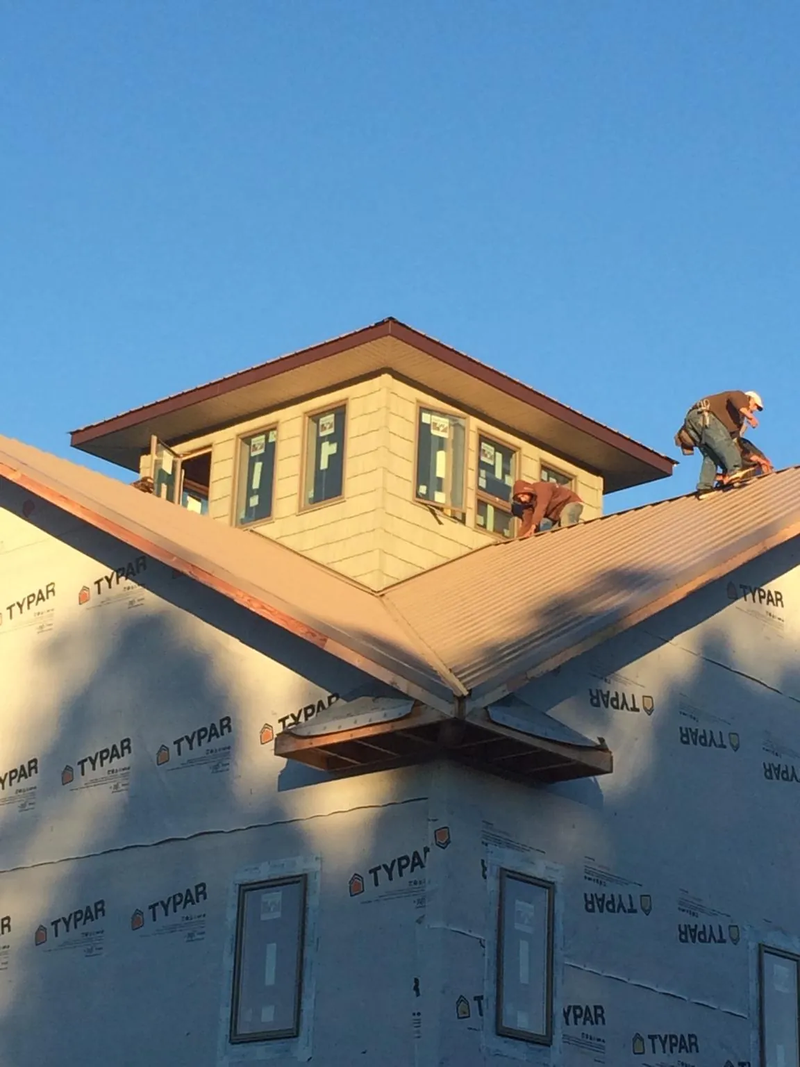 Roofers working around a rooftop cupola on a new metal roof at sunset — Roof Waterproofing in Pine Meadow by Roofing Brothers